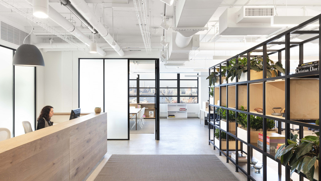 A person sitting at a desk in a room with glass walls.